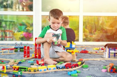 Ahşap tren ile oynayan çocuklar. Toddler çocuk tren ve araba ile oynamak. Okul öncesi ve Anaokulu çocuk için eğitici oyuncaklar. Evde oyuncak demiryolu ile oynarken sevimli çocuk