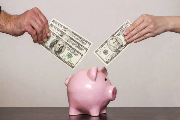 Hands of young men and young women invest money in the piggy bank for the family budget. Couple saves money with piggy bank. — Stock Photo, Image