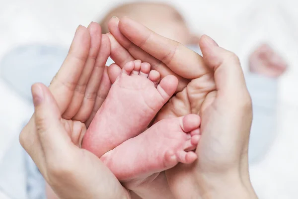 Bebek bacakları. Annenin elinde yeni doğmuş bebek ayakları. Bebek ayakları annelerin eline kapılmış — Stok fotoğraf