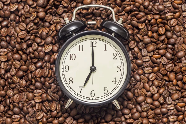 Zwarte klok en koffiebonen als achtergrond. Wekker in koffiebonen. Koffie tijd concept — Stockfoto