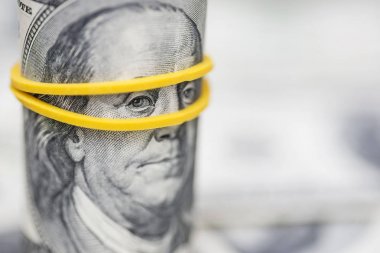 Rulo 100 dolarlık banknotlar, kauçuk bant ile Franklin'in gözleri üzerinde bir vurgu ile
