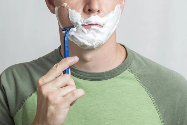 Man shaving. Man with razor and shaving foam on his face. Body care and male hygiene concept