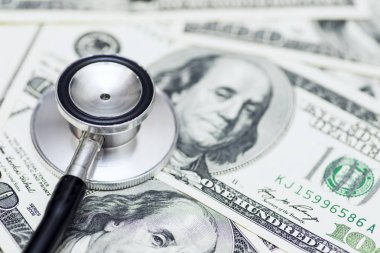 Dolarların üzerinde steteskop var. Tıbbi masraflar. Sağlık hizmeti ödemesi konsepti. Piyasa, ekonomi ve faiz oranlarının analizi kavramı