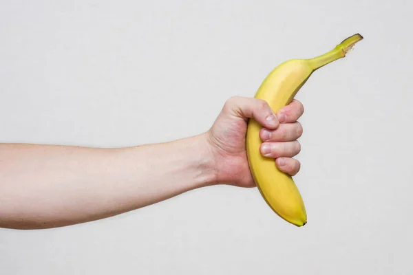 Ruka mladého muže, která drží krásný, čerstvý, žlutý banán. Mužská ruka držící banán — Stock fotografie
