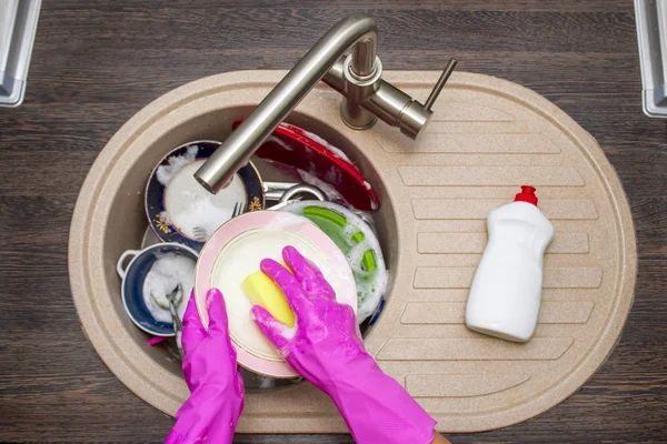 Mutfak yemekleri yıkamak kadının ellerini kapatın. Eller kırmızı kauçuk eldivenlere bulaşıkları yıkıyor. Üst görünüm — Stok fotoğraf