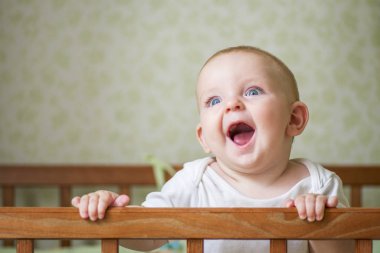 Yatakta duran şirin bir bebek. Yatakta oynayan gülümseyen çocuk. Kreşteki çocuk portresi. Mutlu çocukluk kavramı