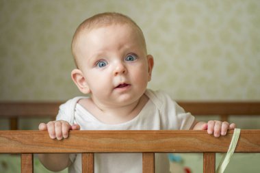 Yatakta duran şirin bir bebek. Yatakta oynayan gülümseyen çocuk. Kreşteki çocuk portresi. Mutlu çocukluk kavramı