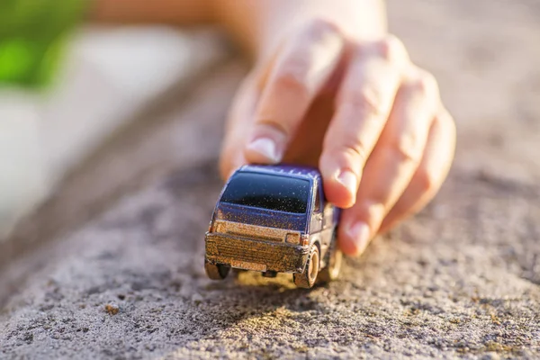 Niño juega con coche de juguete. Niño jugando con el juguete del coche en la puesta del sol — Foto de Stock