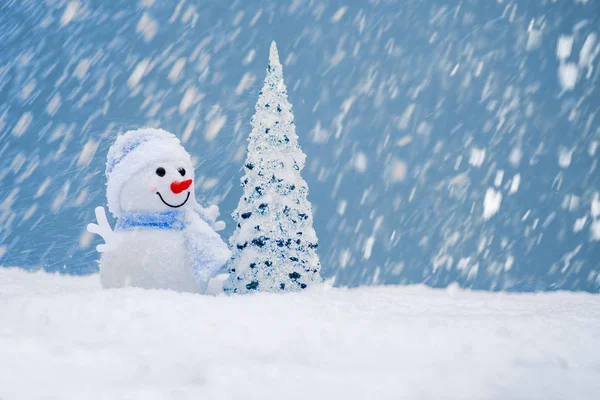 Happy snowman with Christmas tree in winter scenery with copy space. Christmas background with snowman