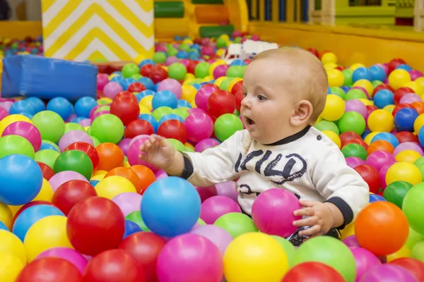 Zona de juegos con pista de pelota cubierta. Joyful small kid having fun at indoor play center. El niño está jugando con bolas de colores en la piscina de balonmano. Vacaciones o cumpleaños — Foto de Stock