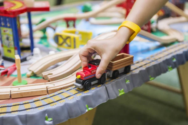 Ребенок играет с деревянной игрушкой, строит игрушечную железную дорогу дома или в детском саду — стоковое фото