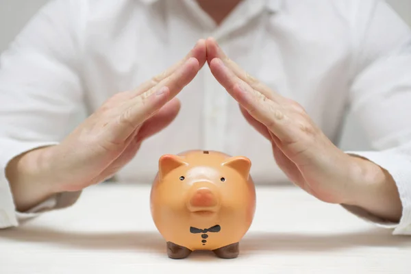 Hands protect the piggy bank. Concept for finance insurance, protection, safe investment or banking with hands over a piggy bank — Stock Photo, Image