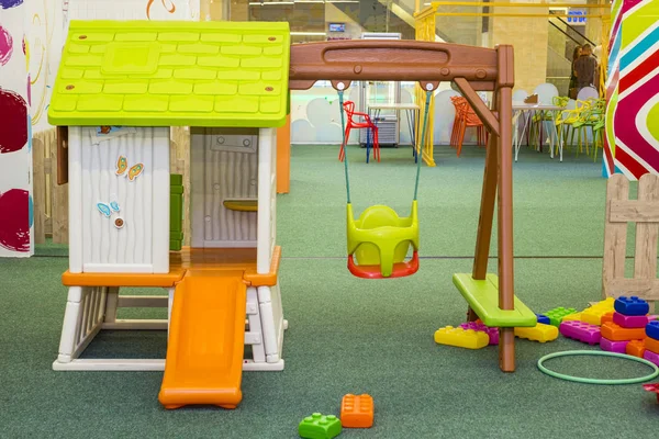 Çocuk eğlence merkezinin altında yeşil bir paspas olan çok renkli bir slayt. Bir sürü oyuncağı olan çocuk odası. — Stok fotoğraf