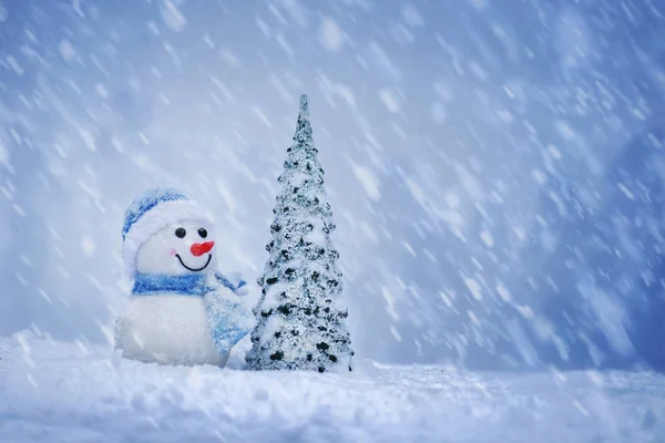 Feliz Navidad y feliz año nuevo tarjeta de felicitación. Terrible muñeco de nieve con árbol de Navidad de pie en el paisaje de Navidad de invierno — Foto de Stock