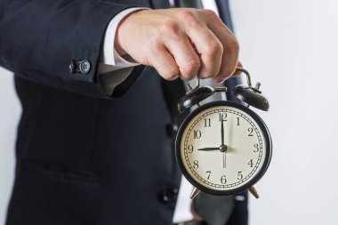 İş adamı alarm saatini tutar. İş zamanı yönetimi konsepti. Elinde çalar saat olan bir iş adamı.