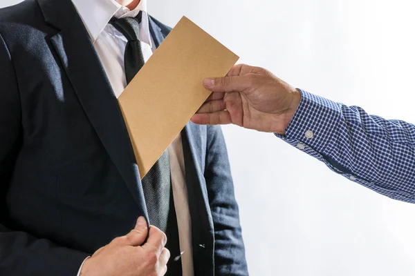 A man giving bribe money in a brown envelope to another businessman in a corruption scam. Bribery and corruption concept