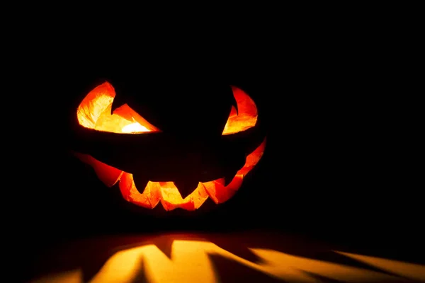 Halloween dýně úsměv a děsivé oči pro párty noc. Zblízka pohled na strašidelné Halloween dýně s očima zářící uvnitř na černém pozadí. Selektivní zaměření — Stock fotografie