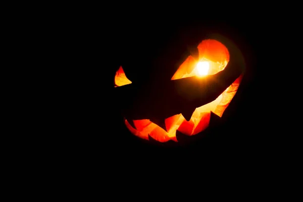 Halloween dyniowy uśmiech i przerażające oczy na noc party. Zamknij widok przerażający Halloween dyni z oczami świecącymi wewnątrz na czarnym tle. Skupienie selektywne — Zdjęcie stockowe