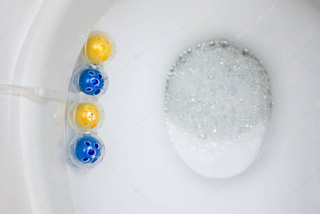 Clean toilet bowl with a cleaning and refreshing balls. Multi-colored balls of toilet bowl cleaner.