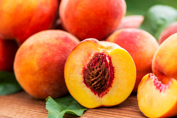 Fresh peaches on wooden table. Ripe peaches with leaves on a wooden board.