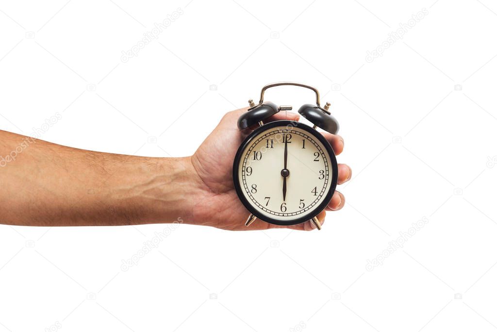 Man is holding black alarm clock in one hand on white background.