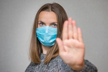 Yüzünde koruyucu maske takan kadın Coronavirus salgınını durdurmak için el hareketi yapıyor. Kadın yüzüne odaklan. Virüsü durdur..