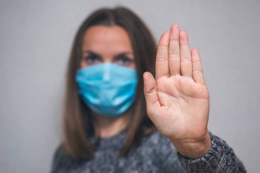 Yüzünde koruyucu maske takan kadın Coronavirus salgınını durdurmak için el hareketi yapıyor. Maskeli kadın elini uzatmaya odaklandı. Virüsü durdur..