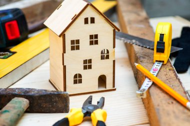 Aletlerle çevrili ahşap ev oyuncağı. Ev tamiri kavramı. Ev tadilatı. Evi yenile.