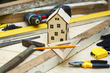 Aletlerle çevrili ahşap ev oyuncağı. Ev tamiri kavramı. Ev tadilatı. Evi yenile.