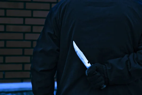 Man with the knife behind his back. Man holding sharp knife behind his back.