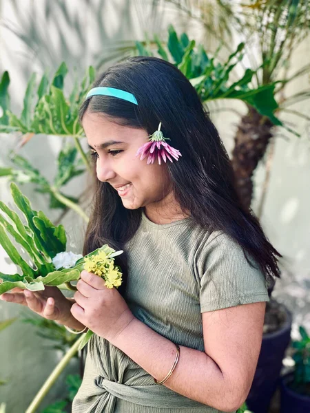 Elinde çiçekle gülümseyen Hintli kız çocuğu.