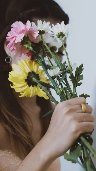 Yüzünü renkli çiçeklerden saklayan bir kadın..