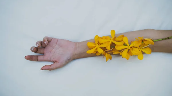 Kolunda sarı çiçekler olan bir kadın..