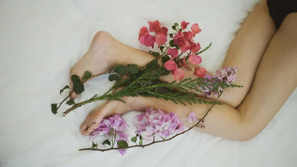 Ayaklarına çiçekler sarılmış bir kadın..