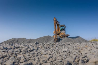 Ön uç kova yükleyici açık bir depodaki bir yığın kargoya yükler..