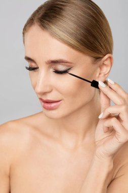 Sıvı eyeliner fırçası ile uygulama güzel sarışın kadın portresi. Doğal makyaj. Güzellik kadını mükemmel deri ile. Makyaj kavramı.