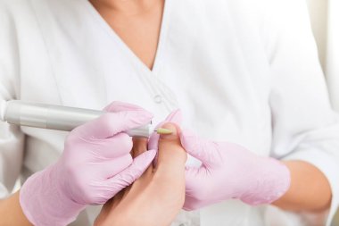 Elektrikli makine kullanan profesyonel donanım pedikürü. Tıbbi pedikür yapan hasta, podiyatriste gidiyor. Özel elektrikli aletle ayak soyma. SPA Salonu 'nda ayak tedavisi..