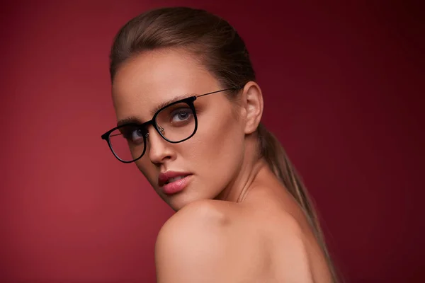 Attraktiv Kvinna Fyrkantiga Glasögon Tittar Kameran Röd Bakgrund Porträtt Ung — Stockfoto