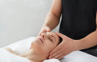 Genç güzel kadın anti-aging yüz masaj zevk. Erkek terapist kadın istemciye baş masajı yapma. Profesyonel masör. Gevşeme, güzellik, spa, vücut ve yüz tedavi kavramı. 