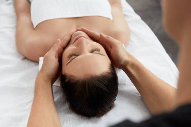 Genç güzel kadın anti-aging yüz masaj zevk. Erkek terapist kadın istemciye baş masajı yapma. Profesyonel masör. Gevşeme, güzellik, spa, vücut ve yüz tedavi kavramı. 