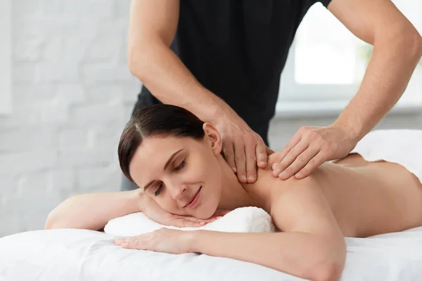 年轻美丽的女人享受背部按摩 专业的按摩治疗师正在公寓里治疗一名女性病人 身体和面部治疗的概念 家庭按摩 — 图库照片