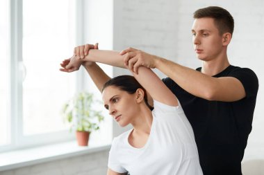 Bayan hasta fizyoterapist ile fiziksel egzersizleri yapıyor. Erkek terapist tedavi omuz genç sporcunun yaralandı. Travma sonrası rehabilitasyon, spor fizik tedavi, kurtarma kavramı.