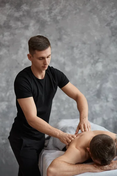 Jovem Bonitão Desfrutando Uma Massagem Nas Costas Massagista Profissional Está — Fotografia de Stock