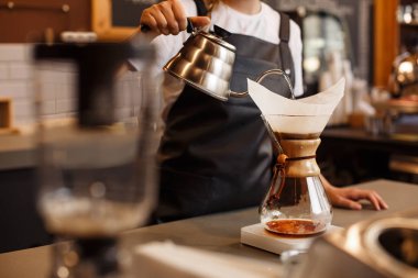 Kahve makinesi ve su ısıtıcısının üzerine dökülen kimyasallarla kahve hazırlayan profesyonel barista. Kahve yapan genç bir kadın. Kahve demlemenin alternatif yolları. Kahve dükkanı konsepti.