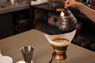 Kahve makinesi ve su ısıtıcısının üzerine dökülen kimyasallarla kahve hazırlayan profesyonel barista. Kahve yapan genç bir kadın. Kahve demlemenin alternatif yolları. Kahve dükkanı konsepti.