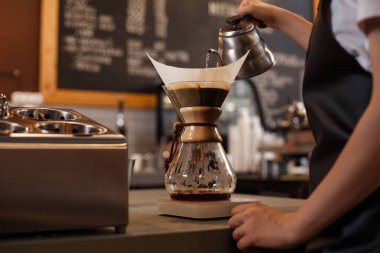 Kahve makinesi ve su ısıtıcısının üzerine dökülen kimyasallarla kahve hazırlayan profesyonel barista. Kahve yapan genç bir kadın. Kahve demlemenin alternatif yolları. Kahve dükkanı konsepti.
