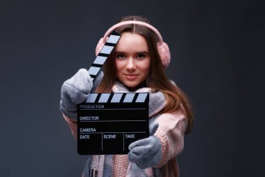 Stüdyoda Noel videosu çektiği için direktör alkış tahtasıyla örgü ören güzel, güzel bir kız. Film yapımcısı alkışlıyor. Işıklar, kamera, motor. Kış tatili başlıyor.