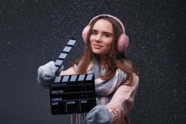 Stüdyoda Noel videosu çektiği için direktör alkış tahtasıyla örgü ören güzel, güzel bir kız. Film yapımcısı alkışlıyor. Işıklar, kamera, motor. Kış tatili başlıyor.