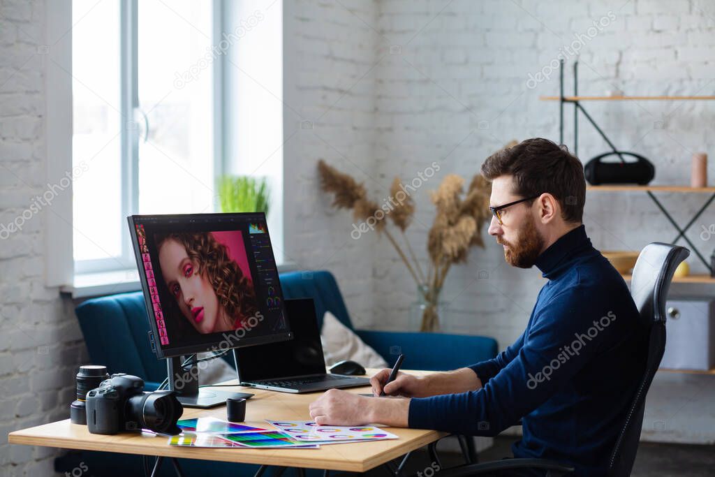 Retouching images in special program.Portrait of graphic designer working in office with laptop,monitor,graphic drawing tablet and color palette.Retoucher workplace in photo studio.Creative agency