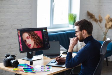 Özel programdaki resimler alınıyor. Dizüstü bilgisayar, monitör, grafik çizim tableti ve renk paleti ile çalışan grafik tasarımcısının portresi. Fotoğraf stüdyosundaki çalışma yeri. Yaratıcı ajans